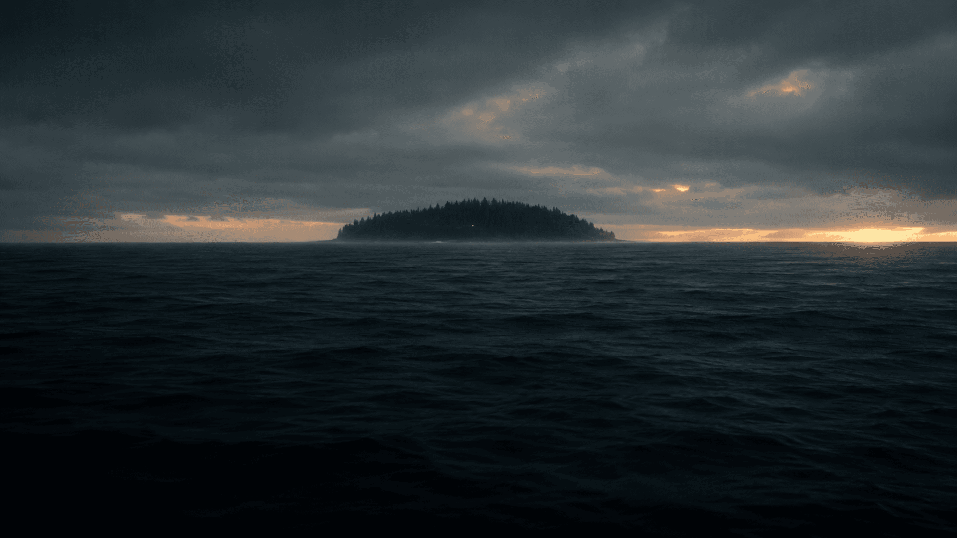 An island on the horizon under a heavy, overcast North Atlantic sky, seen from the open sea at dusk.